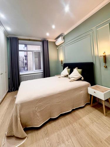a bedroom with a large bed and a window at Central Park Apart in Karagandy