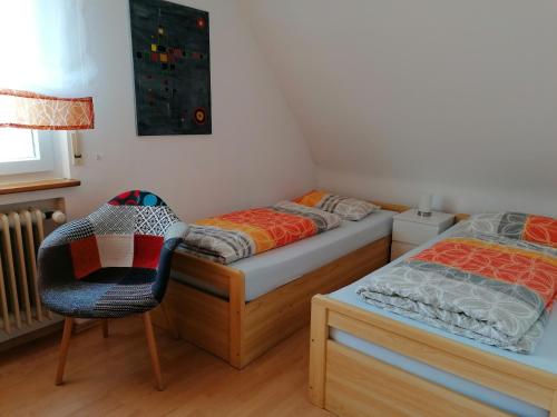 a bedroom with two twin beds and a chair at Ferienwohnung Kirsch-kern in Mössingen