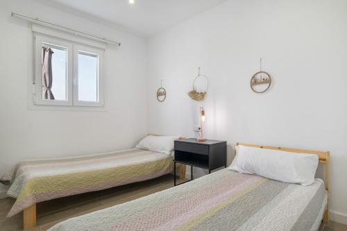 two beds in a white room with a window at Casa Mevak in Chiclana de la Frontera