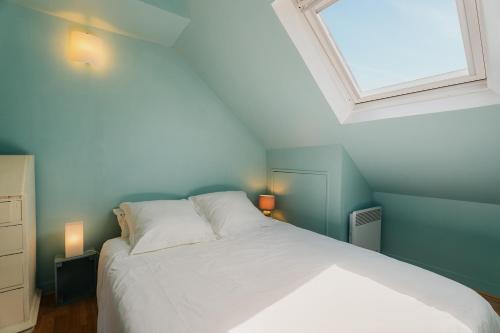 una camera da letto con un letto bianco e una finestra di Les Mouettes de Cancale a Cancale