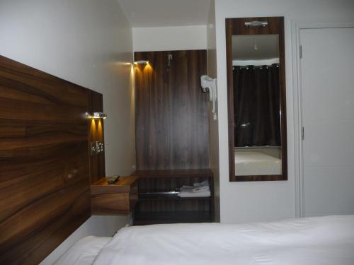 a bedroom with a bed with a wooden headboard and a mirror at Heathrow-Windsor Guest House in Slough