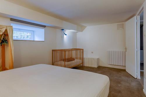 a bedroom with a white bed and a crib at Appart Flaviac in Flaviac