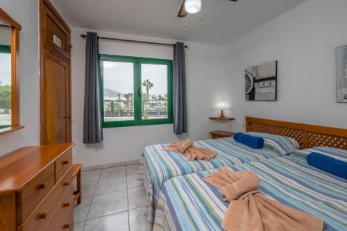 1 dormitorio con 2 camas, vestidor y ventana en Jardin Del Sol 30, en Playa Blanca