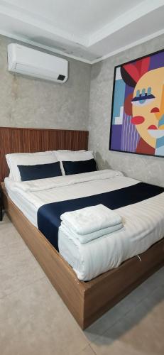 a bedroom with a large bed with a painting on the wall at Townhouse Oak Grey Hotel Near Clark International Airport in Pampang