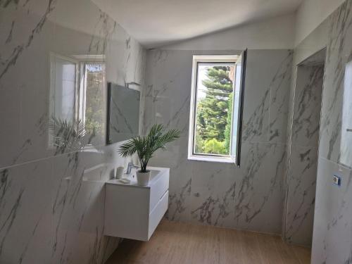 baño blanco con lavabo y ventana en Casa Vacanza L'Orchidea, en Capaccio-Paestum