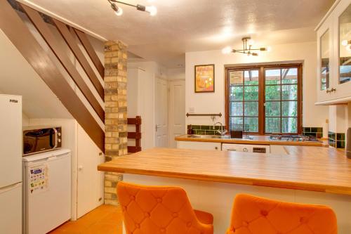 a kitchen with a counter and two orange chairs at Stylish Victorian Terrace in Central Cambridge Pass the Keys in Cambridge