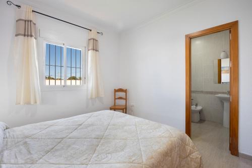 ein weißes Schlafzimmer mit einem Bett und einem Badezimmer in der Unterkunft Chalet La Barrosa in Chiclana de la Frontera