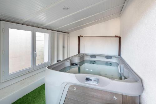 eine große Badewanne in einem Raum mit Fenster in der Unterkunft Jacuzzi Maison pour 11 au calme plage a 500m in Le Cormier
