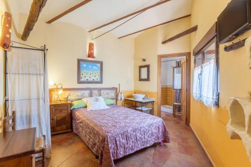 Fuentidueña de TajoにあるEl Tinao De La Petraのベッドと机とテレビのある寝室