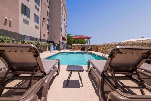 a swimming pool with two chairs next to a building at Comfort Suites El Paso Airport in El Paso