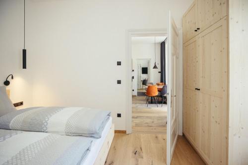 a white bedroom with a bed and a hallway at Freienfeldhof Elstar in Lagundo