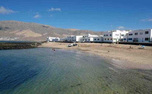 ein Strand mit Gebäuden und Menschen im Wasser in der Unterkunft Casa Rafa in Famara