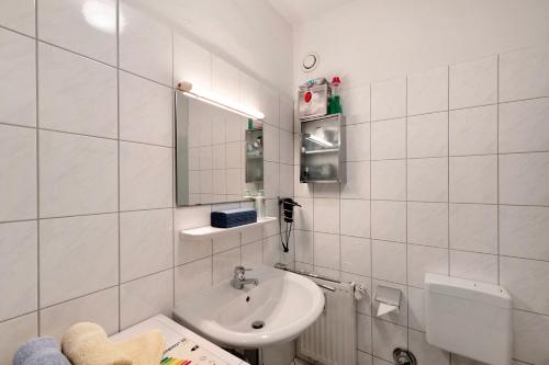 a white bathroom with a sink and a mirror at Kinderfreundliche Wohnung am See in Nienhagen