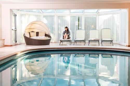 a woman sitting in a chair next to a swimming pool at Alpenhof Lodge Ifinger in Saltusio