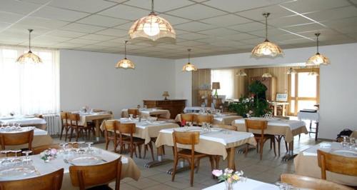 un comedor con mesas blancas, sillas y luces en Hôtel du Marché, en Beauvoir-sur-Mer
