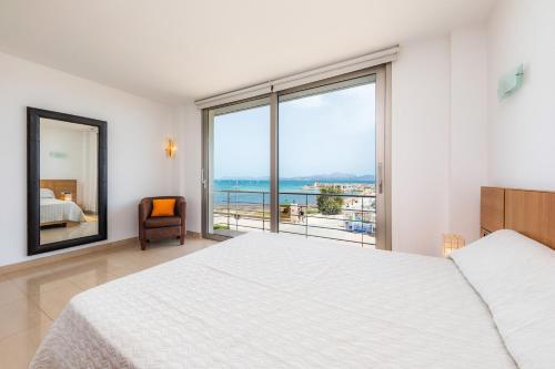 a bedroom with a white bed and a large window at Casa Mulet in Can Picafort