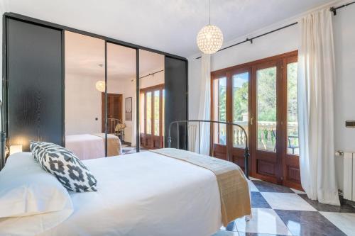 a bedroom with a large white bed and large windows at Villa Manrique in Cala Ratjada