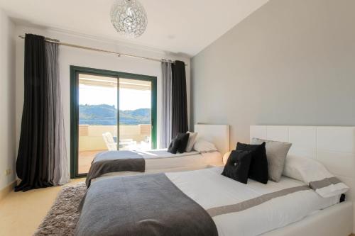two beds in a room with a large window at Modern 2-bed apt Capanes del Golf in Benahavís
