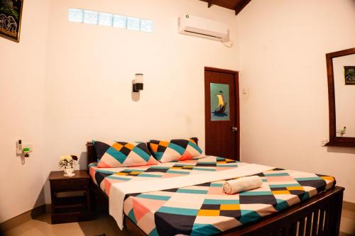 a bedroom with a bed with a colorful blanket at Green Edge Residences in Dambulla