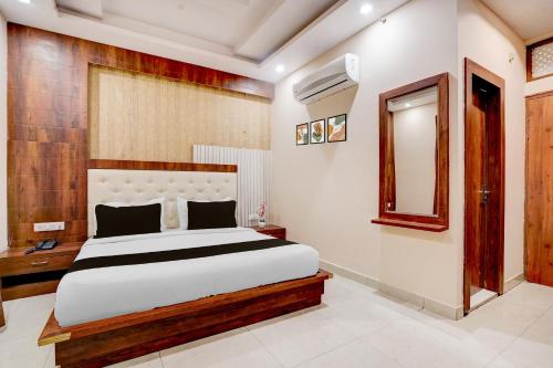 Un dormitorio con una cama grande y un espejo. en Townhouse Oak Dehradun Court Formerly GK Residency, en Dehradun
