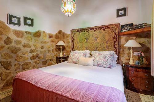 une chambre avec un lit et un mur en pierre dans l'établissement La Cuina De Paqui, à Caserío Calandari