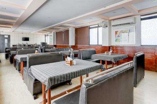 a dining room with tables and chairs in a restaurant at Hotel O Skyland in Ahmedabad