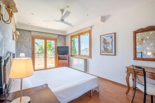 Un dormitorio con una cama, un escritorio y ventanas. en Villa Quesada, en Paguera