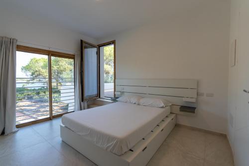 a white bedroom with a bed and a large window at Villa The Beach in Olbia