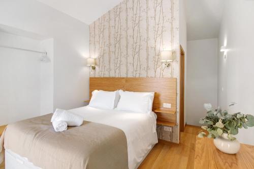 a bedroom with a bed with white sheets and a vase of flowers at Casa do Calhau in Câmara de Lobos