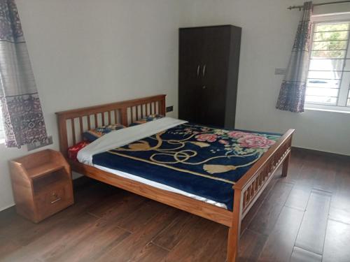 een slaapkamer met een bed en een houten vloer bij Cherry Blossom in Kotagiri