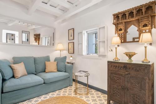 a living room with a blue couch and a wooden cabinet at Casa Castillo con Jardín in Vejer de la Frontera