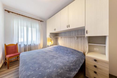 a bedroom with a bed and a chair and a window at Casa Da Rin Elena in Auronzo di Cadore