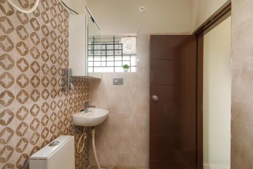 a bathroom with a sink and a toilet and a mirror at The Garden Retreat by StayJadePool2BHKLawn in Berikai