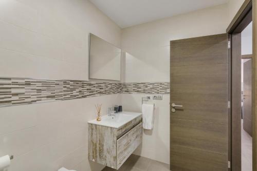 a bathroom with a sink and a wooden door at Edificio Bentejui 2 in Las Palmas de Gran Canaria