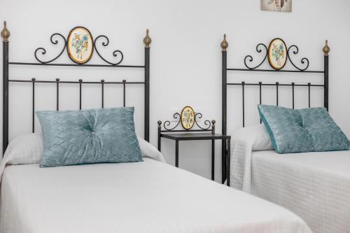 two beds with blue pillows in a bedroom at La Brujita in Chiclana de la Frontera