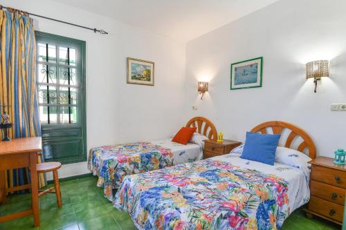 プエルト・デル・カルメンにあるMimosa B1のベッド2台と机と窓のある寝室