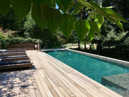 une piscine avec un banc et une terrasse en bois dans l'établissement Château de Jouques, à Gémenos