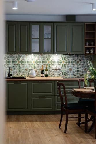 a kitchen with green cabinets and a table at Apartamenty Nad Drwęcą in Brodnica