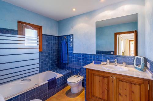 ein blaues Badezimmer mit einer Badewanne, einem WC und einem Waschbecken in der Unterkunft S Estanyol in Colònia de Sant Pere