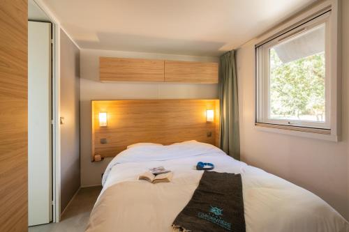 a bedroom with a large white bed with a window at Camping Sunelia L'Argentière in Cogolin