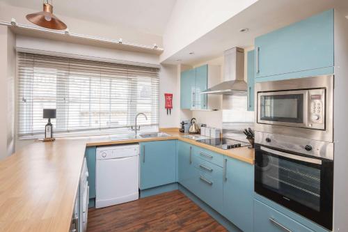a kitchen with blue cabinets and white appliances at Dream Stays Bath - Queen Street Loft Apartment in Bath