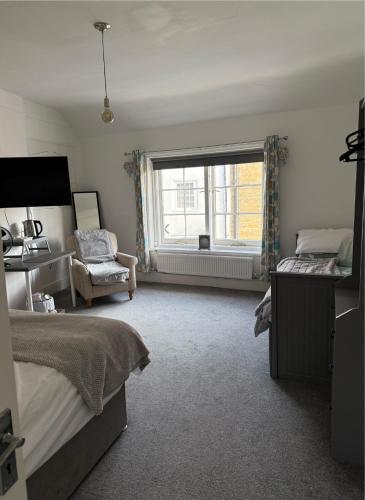 a bedroom with a bed and a window and a chair at Britannia inn in Sherborne