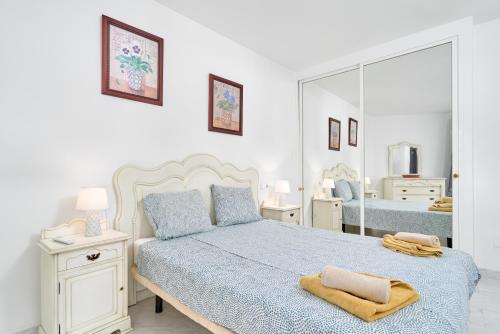 Dormitorio blanco con cama y espejo grande en Casa Alina, en Nerja