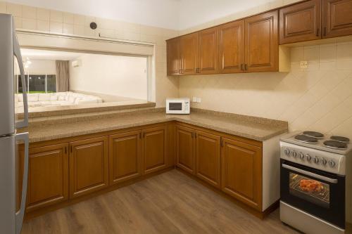 une cuisine avec des armoires en bois et un four à plaques de cuisson dans l'établissement شاليه البرادايس 26 في درة العروس, à Durat Alarous