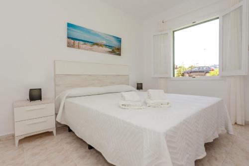 a white bedroom with a bed and a window at Biniforcat 21 in Cala en Forcat