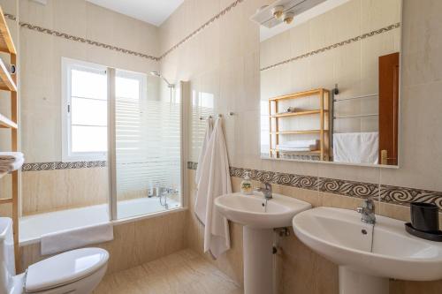 Un baño con dos lavabos, una bañera y un inodoro. en Exclusive Villa - Great Sea View, en Nerja