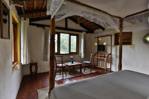 - une chambre avec un lit à baldaquin, une table et des chaises dans l'établissement Natural Mystic Sanctuary, à Deniyaya