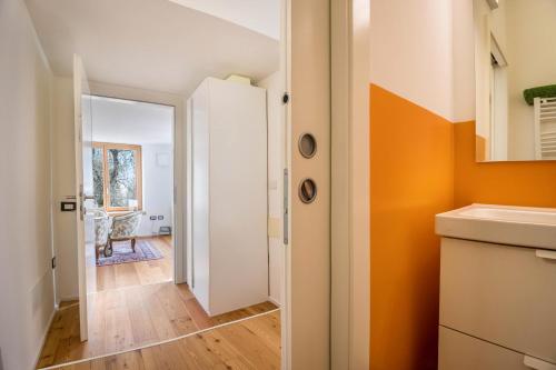 a kitchen with an orange wall and a hallway at Villa Iagra in Tiarno di Sopra