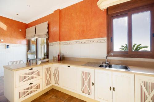 a kitchen with white cabinets and a sink and a window at Carolina Beach House in Chiclana de la Frontera