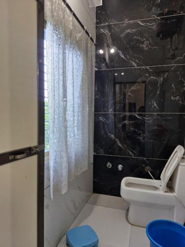 a bathroom with a white toilet and a black wall at TARA Guest House in Ujjain